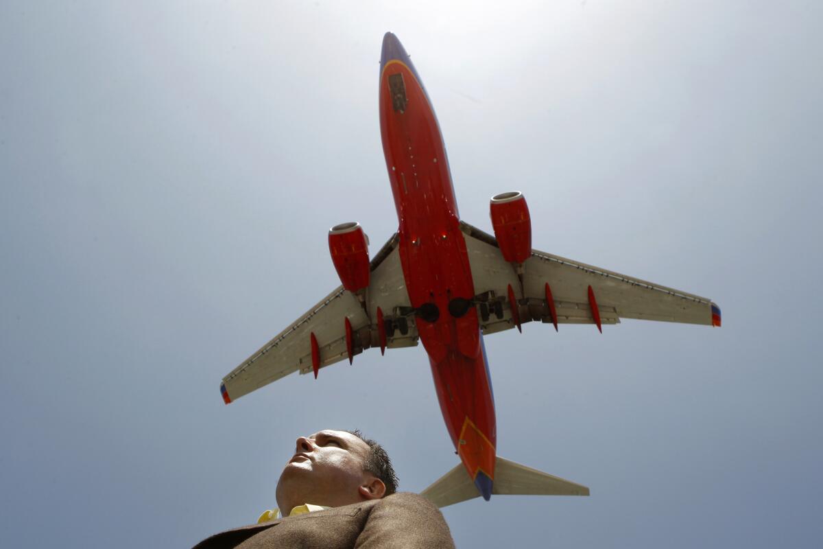 Robert MacLean, a federal air marshal who is contesting his firing for disclosing sensitive security information to the news media, stands beneath a jetliner taking off from John Wayne Airport in Orange County.