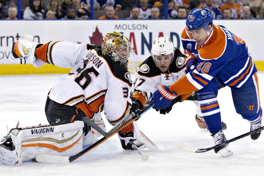 Anaheim Ducks goalie John Gibson, left, makes the save on Edmonton Oilers' Nail Yakupov, right, as Hampus Lindholm defends during first period on Monday.