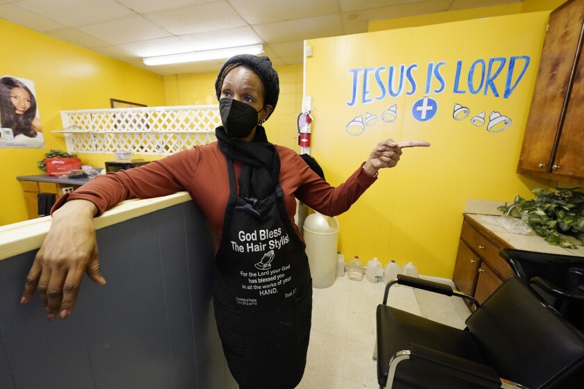 Belinda Smith, owner of Styles of Essence, a hair salon in south Jackson, Miss., speaks of the need to have gallons of water available to use for rinsing clients hair because of the uncertainty of the city's water service, Wednesday, Jan. 26, 2022. The city's ongoing water woes sometimes requires the area water to be shut off without warning. (AP Photo/Rogelio V. Solis)