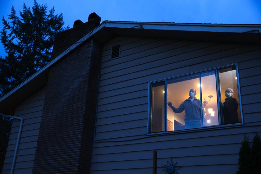 Pat and Bob McCauley, self-quarantined at their home in Kirkland, Wash. can see the red flashing lights of the medics that come and go from the Life Care Center from their window on March 10, 2020. Their good friend, a Life Care resident, died on Sunday of COVID-19. They are mourning him, and anxiously waiting for the results of their COVID-19 tests. They must wear masks when they around each other. Otherwise they need to stay in separate bedrooms and bathrooms in the house. (photo by Karen Ducey)