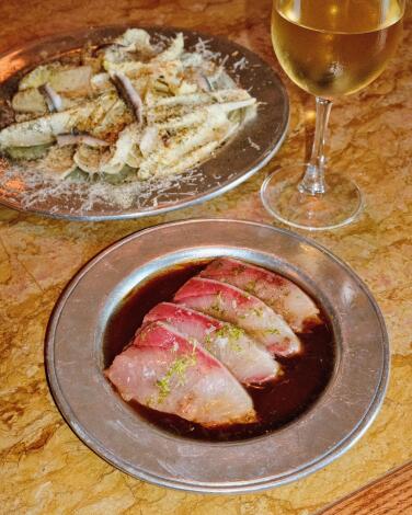 A dish of hamachi crudo ion a silver plate next to a glass of white wine at Barr Seco in Silver Lake.