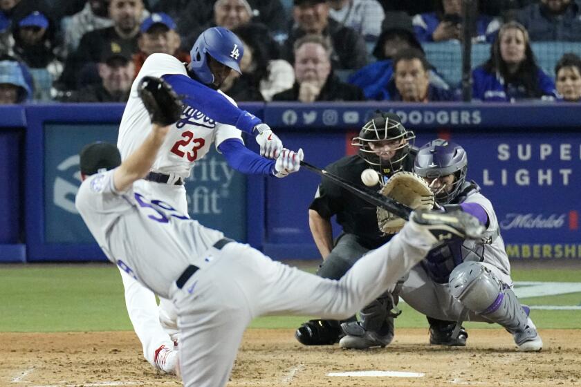 Los Angeles Dodgers' Jason Heyward, second from left, hits a two-run home run as Colorado Rockies relief pitcher Jake Bird, left, watches along with catcher Elias Diaz, right, and home plate umpire Mark Carlson during the fifth inning of a baseball game Monday, April 3, 2023, in Los Angeles. (AP Photo/Mark J. Terrill)