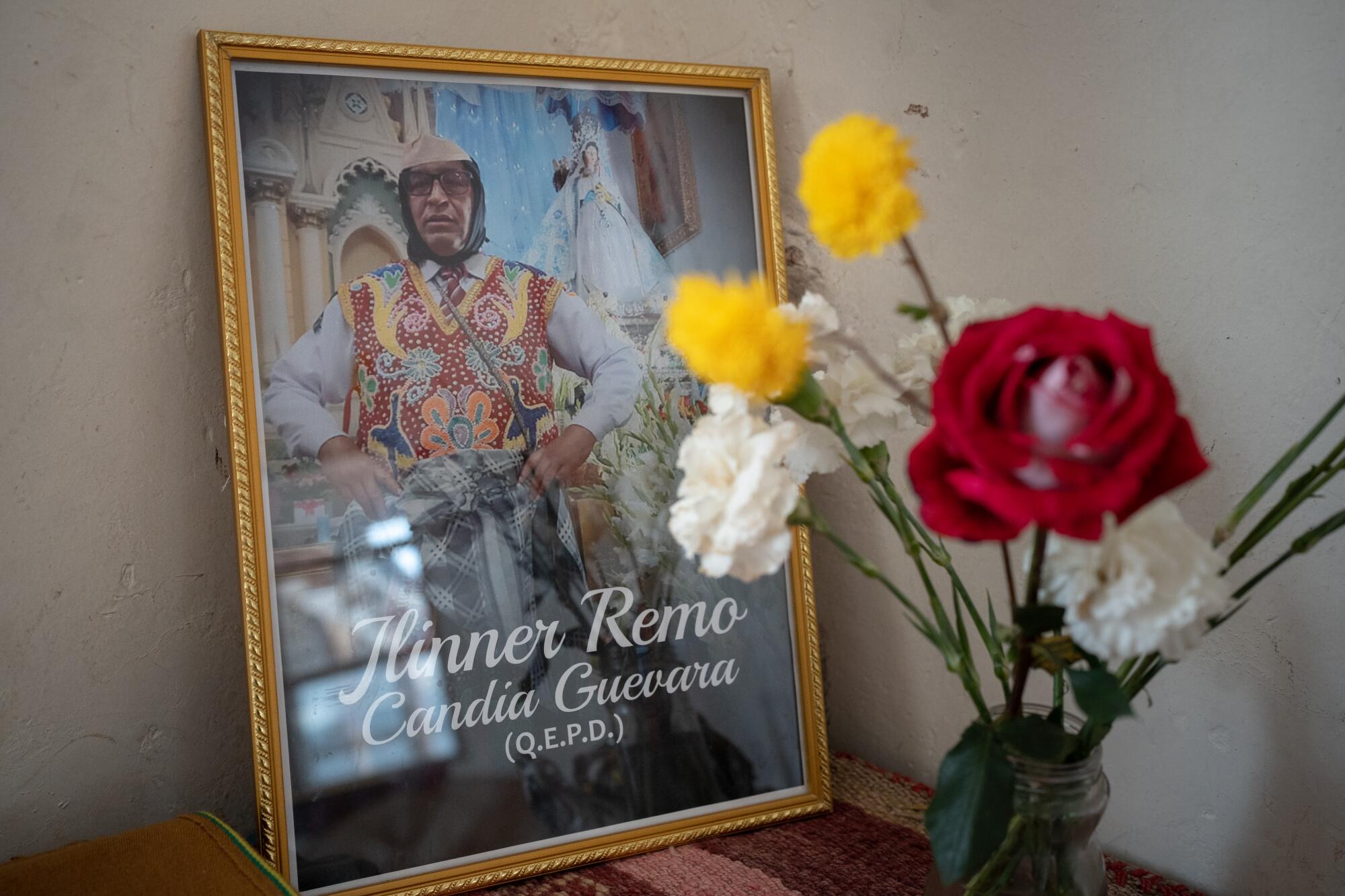 A photograph of Remo Candia Guevara sits beside a vase of flowers.