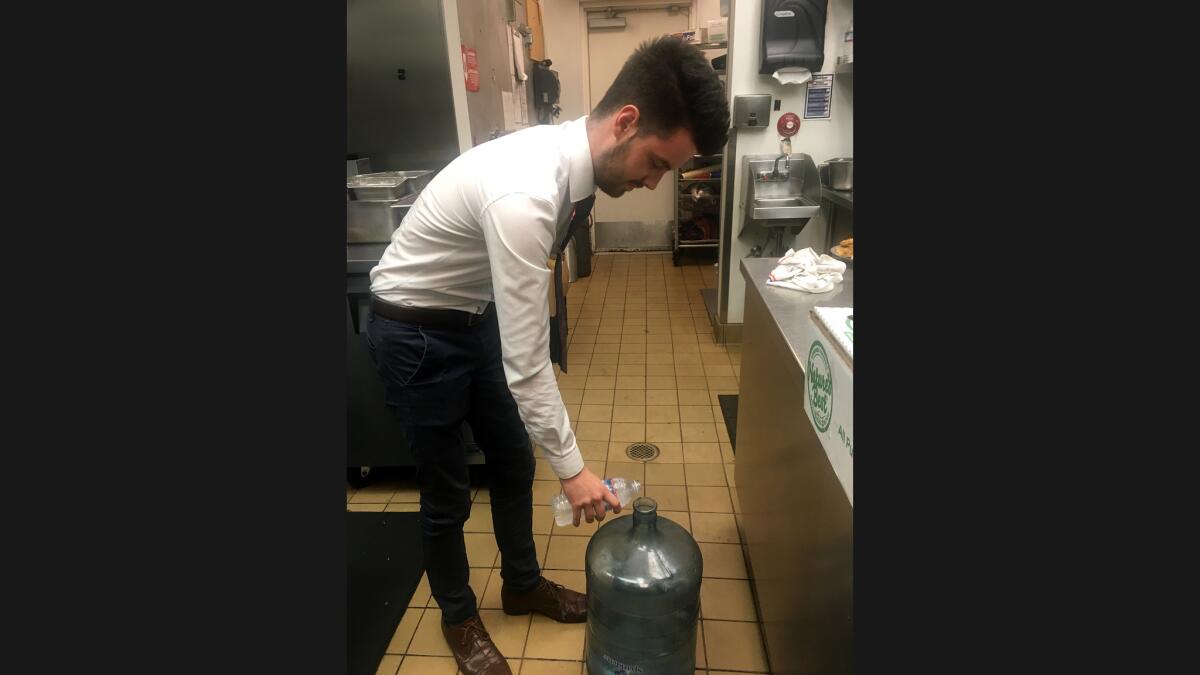 Conor Black, 20, a management intern at the Avalon Grille, pours a diner's leftover bottled water into a 5-gallon container that will be used later to mop floors and nourish plants.