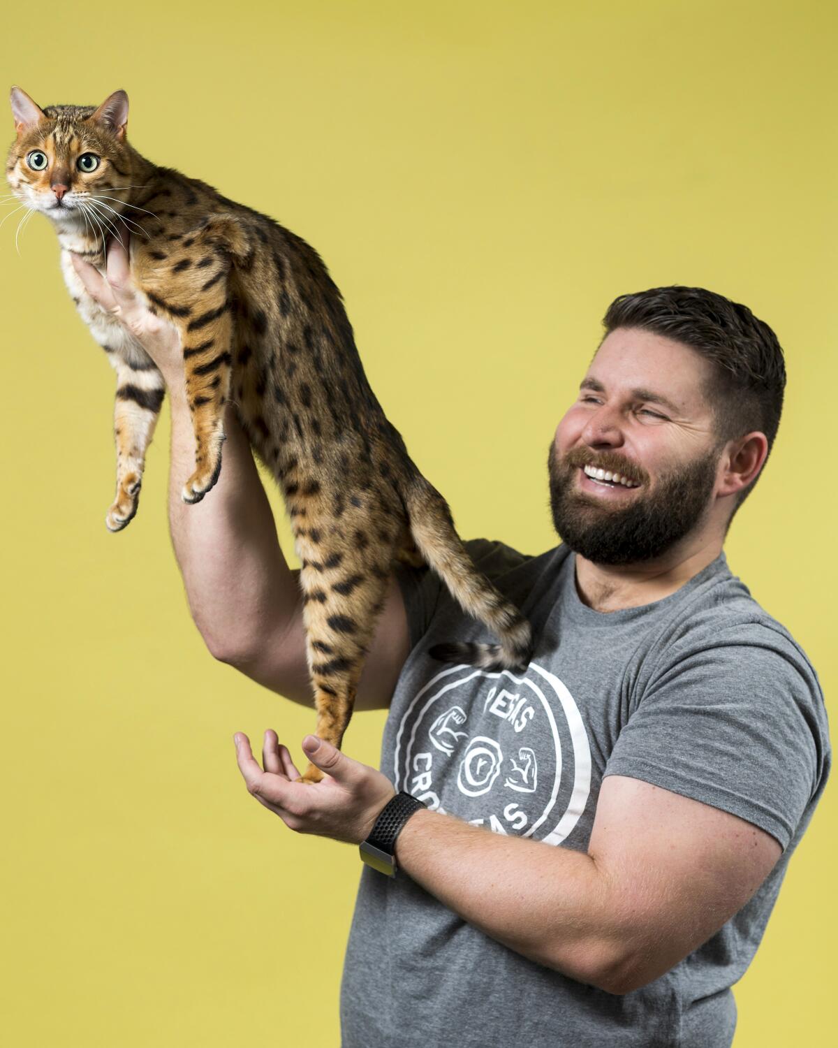 Bobby San Miguel holds up his Bengal named Orestes with one hand under its chest.