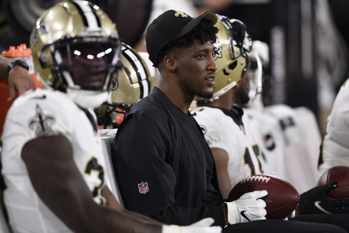 FILE - New Orleans Saints wide receiver Michael Thomas, center, sits on the bench with teammates during the second half of an NFL preseason football game against the Baltimore Ravens, Saturday, Aug. 14, 2021, in Baltimore. Thomas says he won't be able to play this season because of complications related to his recovery from offseason ankle surgery. Saints coach Sean Payton said Thomas will need an additional procedure, but he also credited Thomas' work ethic during his rehabilitation and said the setback had nothing to do with the receiver's approach to his recovery. Thomas posted comments about his setback on social media Wednesday, Nov. 3. (AP Photo/Gail Burton, File)