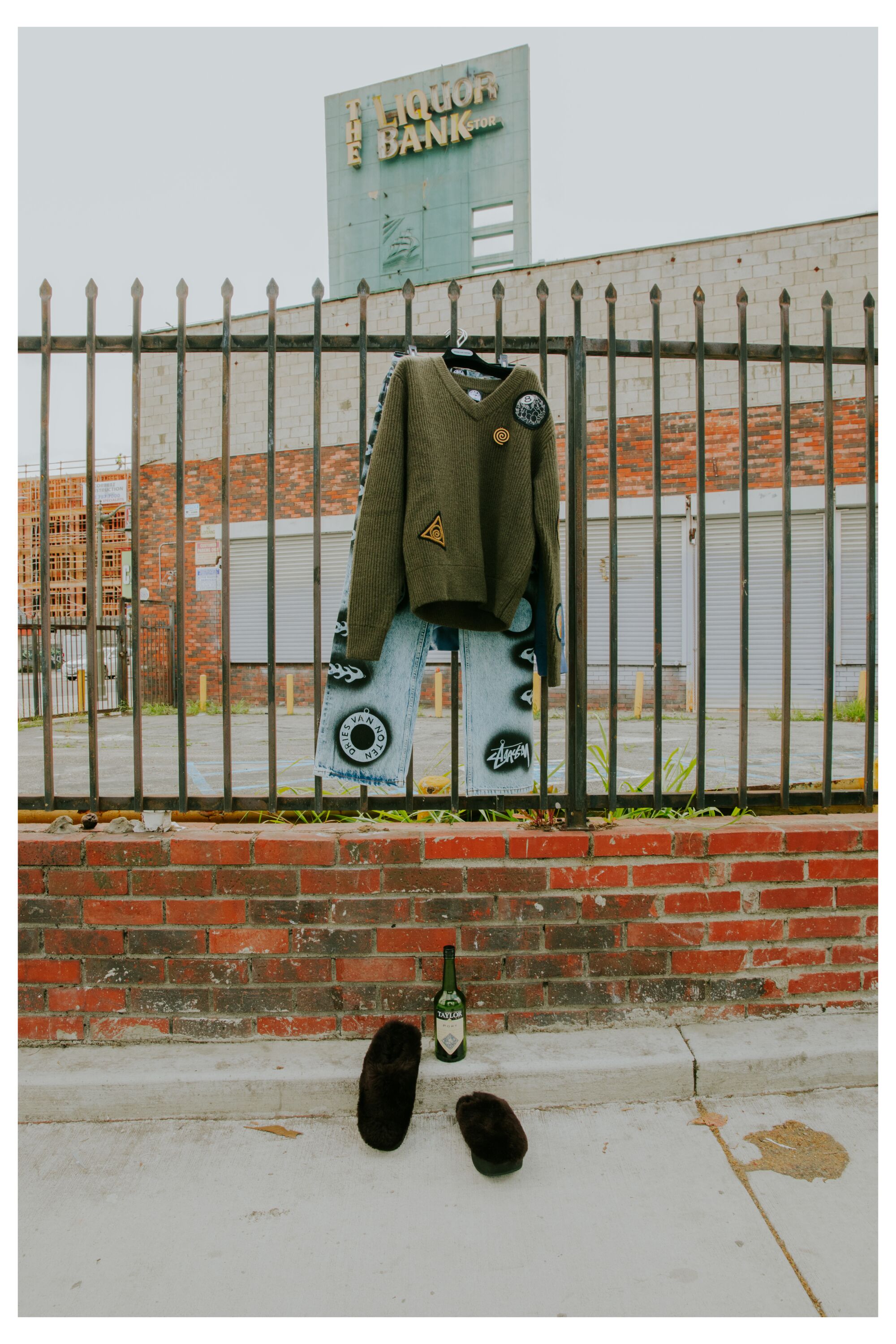 A pair of mules, jeans, and patch knit sweater hang outside the Liquor Bank.
