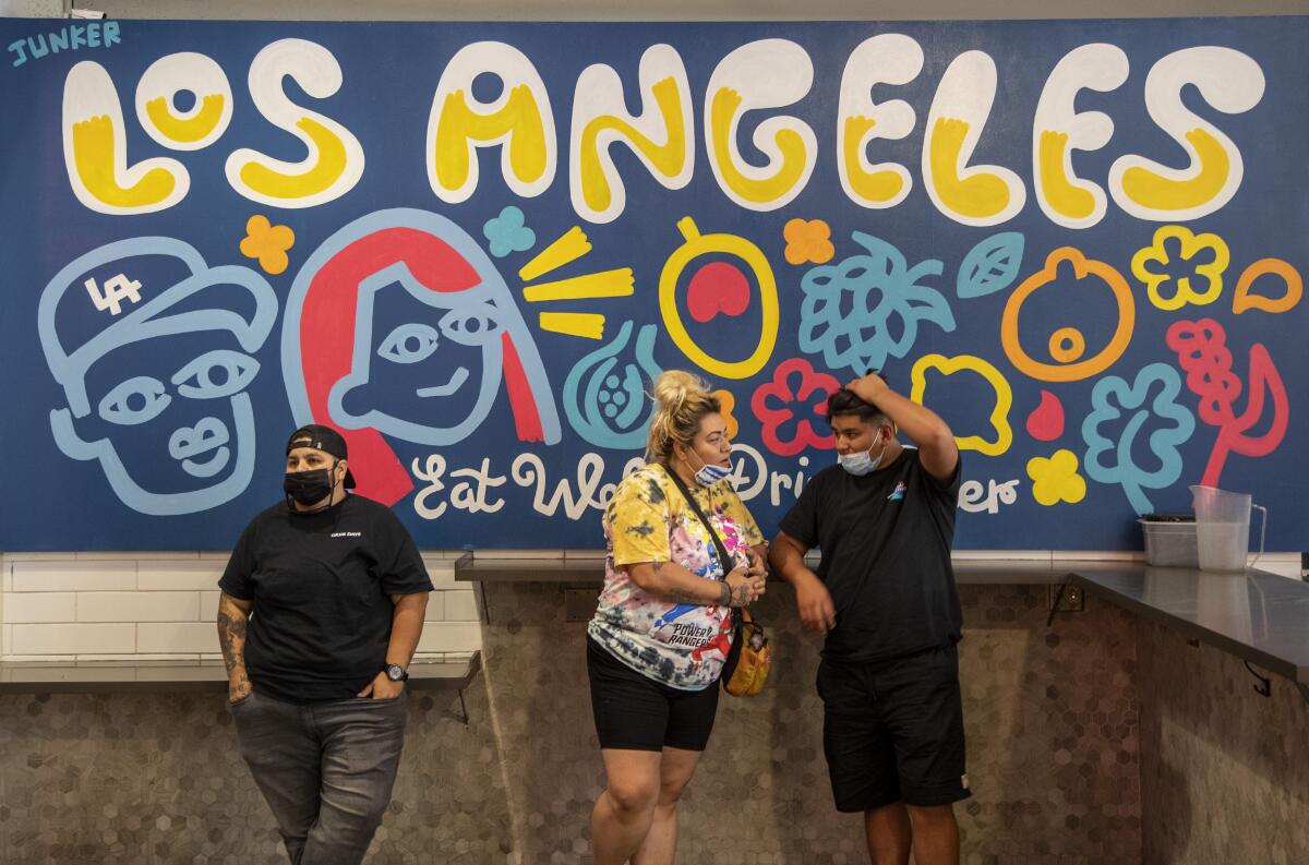 Visitors stand under a mural at Grand Central Market in Los Angeles. 