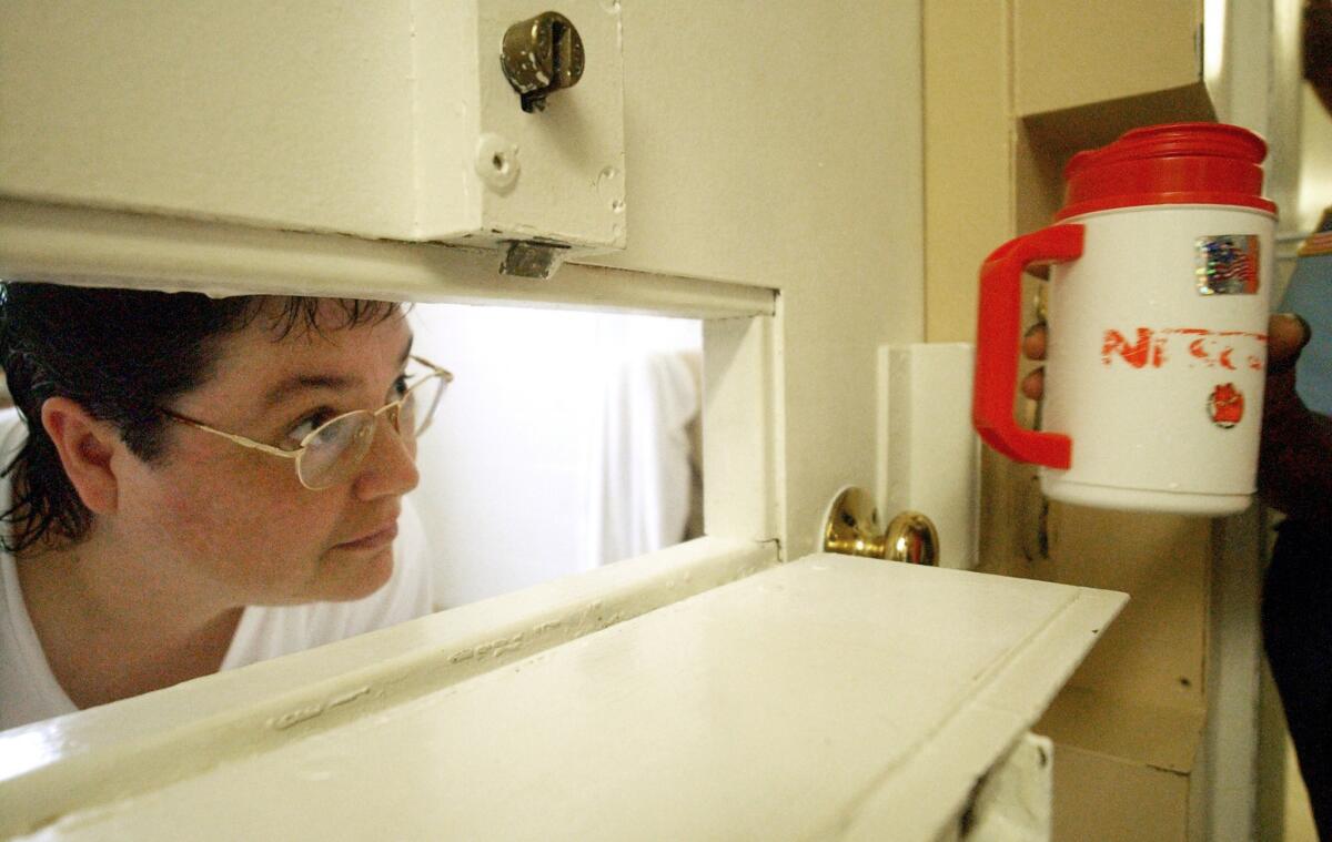 Kelly Renee Gissendaner, the only woman on Georgia's death row, peers through the slot in her cell door as a guard brings her a cup of ice at Metro State Prison in Atlanta last year. Officials postponed her scheduled execution after the lethal injection drug cocktail planned for use in her execution looked cloudy.