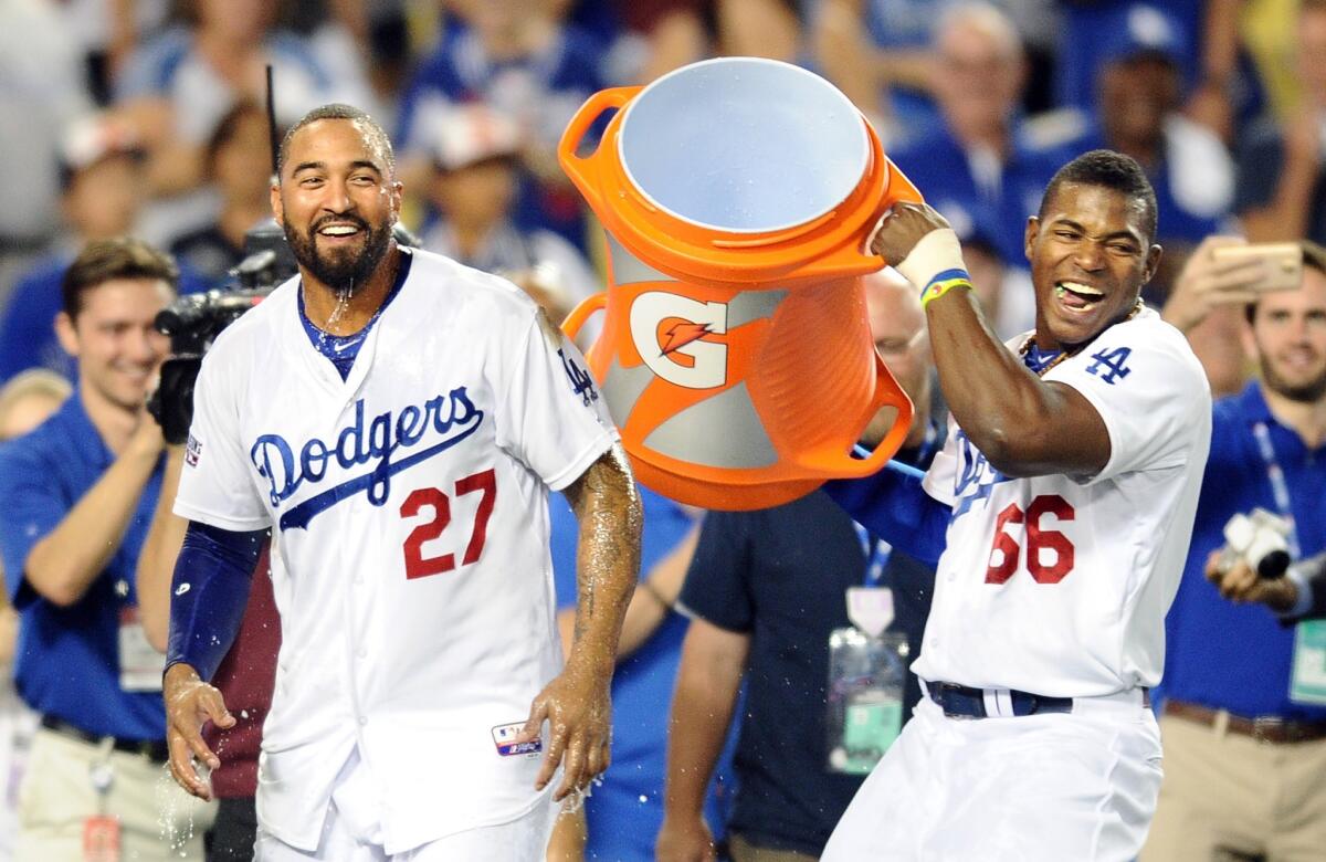 Dodgers right fielder Matt Kemp (27) is drenched in water after getting a shower from teammate Yasiel Puig (66) as they celebrate their 3-2 victory over the Cardinals.
