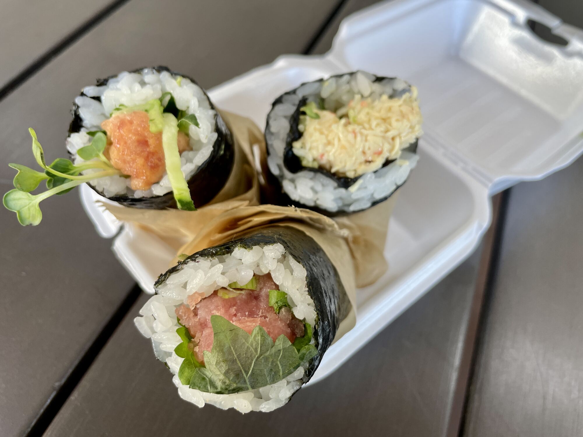 three hand rolls in a a takeout container 