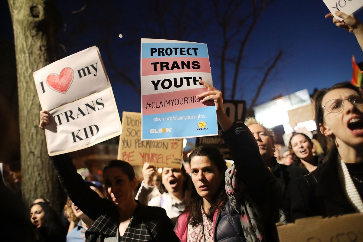 Protesters hold signs supporting transgender youth at a rally