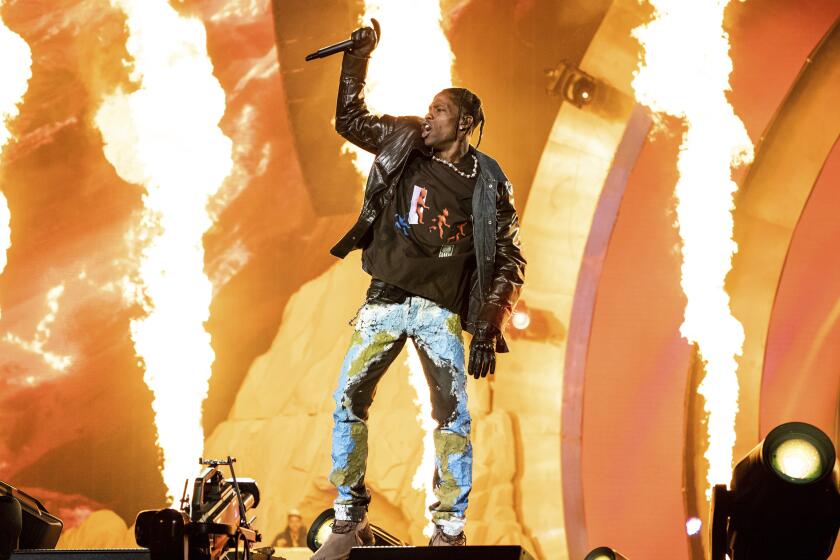Travis Scott performs onstage with flames behind him