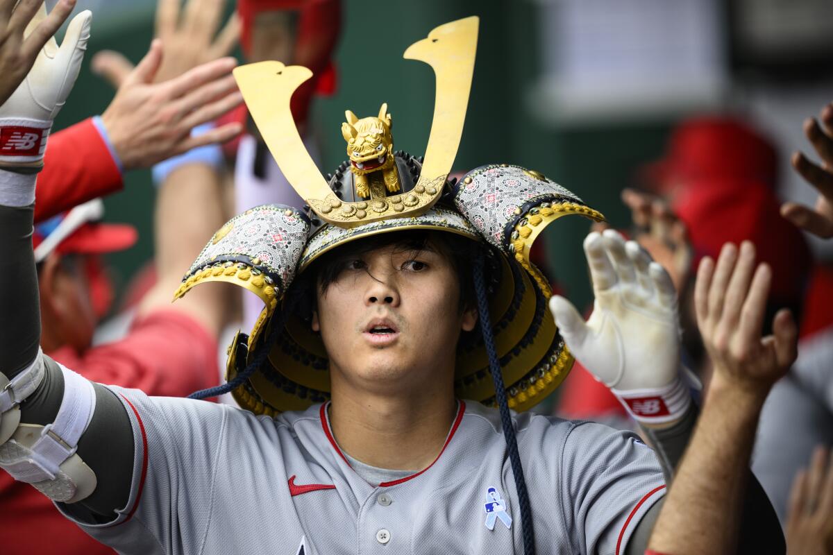 A baseball player wearing a plastic toy headdress gives high-fives.