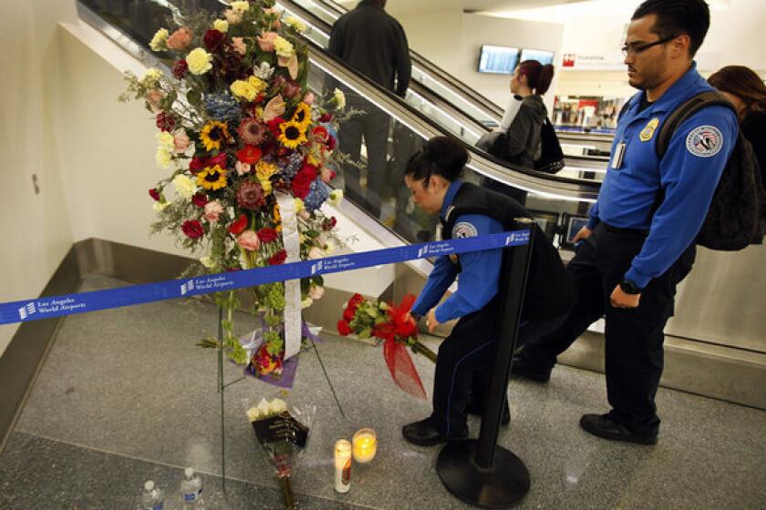 Transportation Security Administration agents leave flowers and say a prayer at a memorial at LAX.