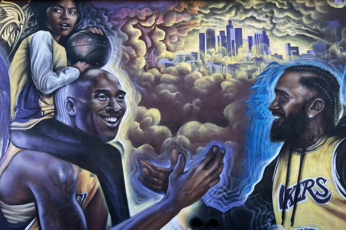 A mural shows Kobe Bryant shaking hands with Nipsey Hussle with his daughter on his shoulders.