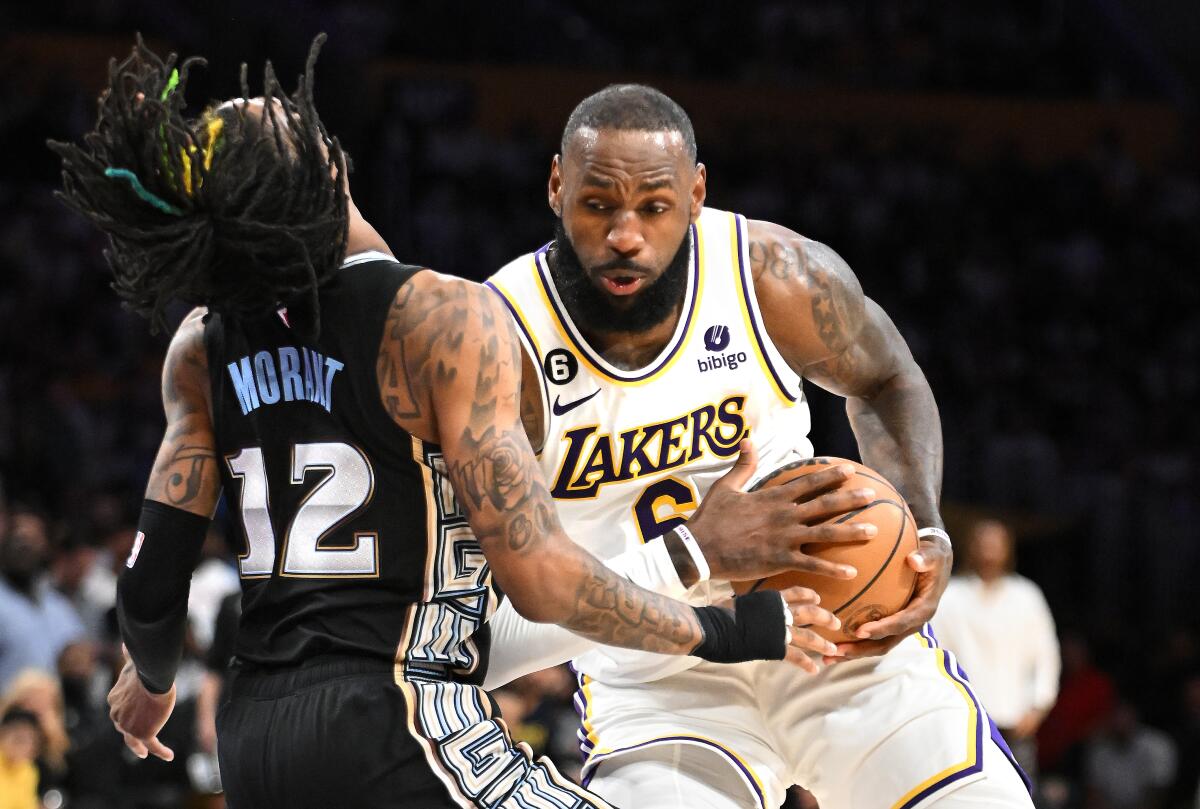 Lakers forward LeBron James powers his way past Grizzlies guard Ja Morant to score a basket.