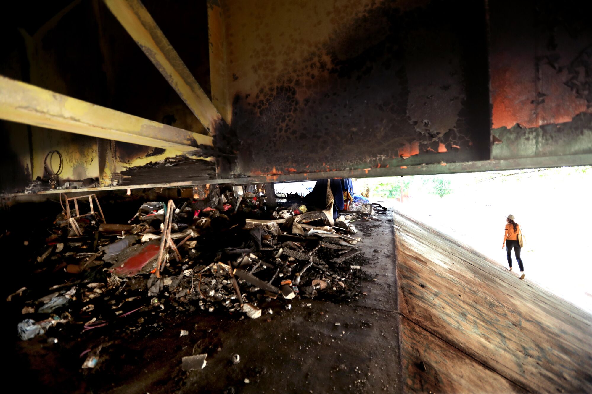 A person walks under a freeway with burned debris