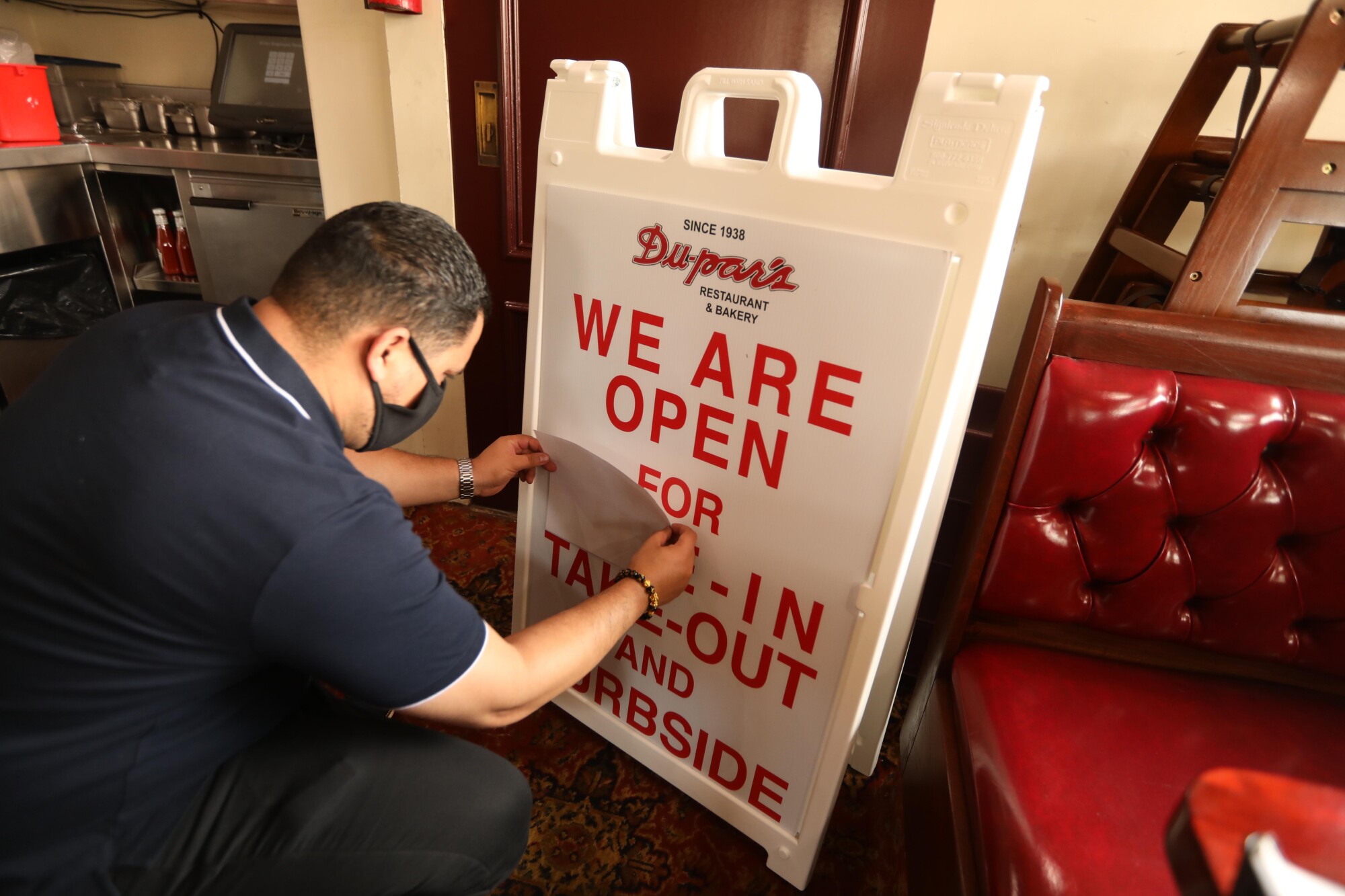 Martin Tario, who co-owns Du-par's with his wife, Frances, covers up "dine in" on a sign at the restaurant.