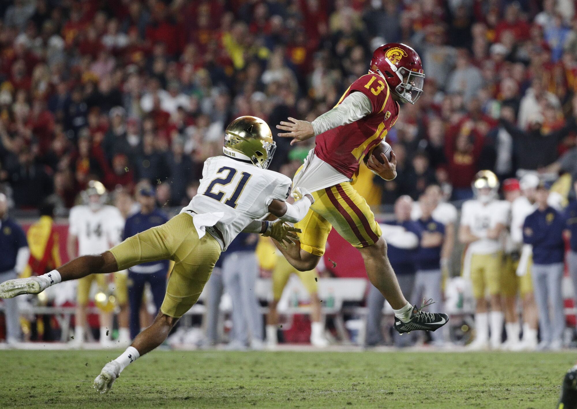 USC quarterback Caleb Williams evades a tackle attempt by Notre Dame cornerback Jaden Mickey