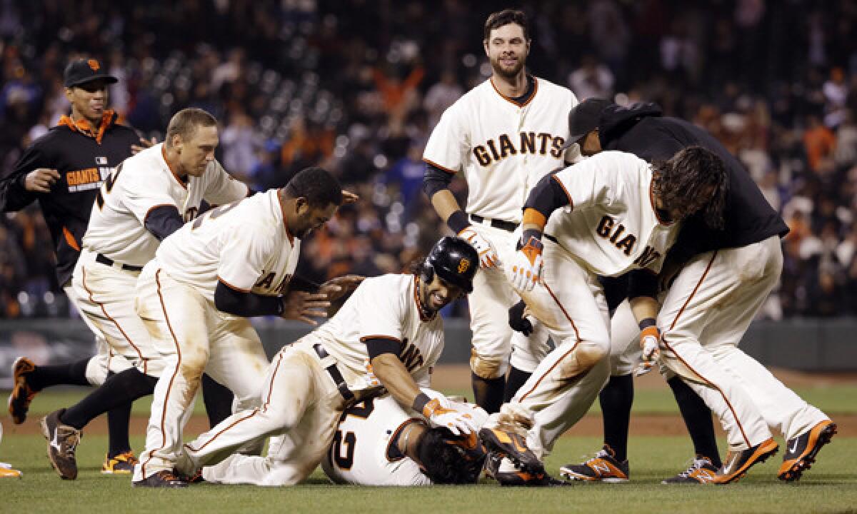 San Francisco Giants catcher Hector Sanchez, bottom center, is mobbed by his teammates after driving in the winning run in the bottom of the 12th inning of the Dodgers' 3-2 loss.