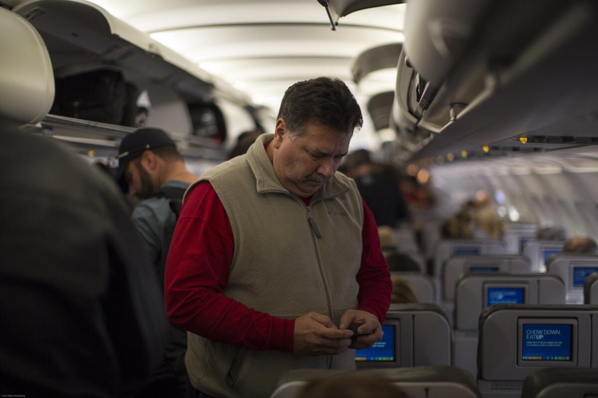 A passenger on JetBlue Airways checks his cellphone before he disembarks at Long Beach Airport. A flight attendants union argues that the FAA violated rule-changing procedures when it allowed passengers to use electronic devices during takeoffs and landings.