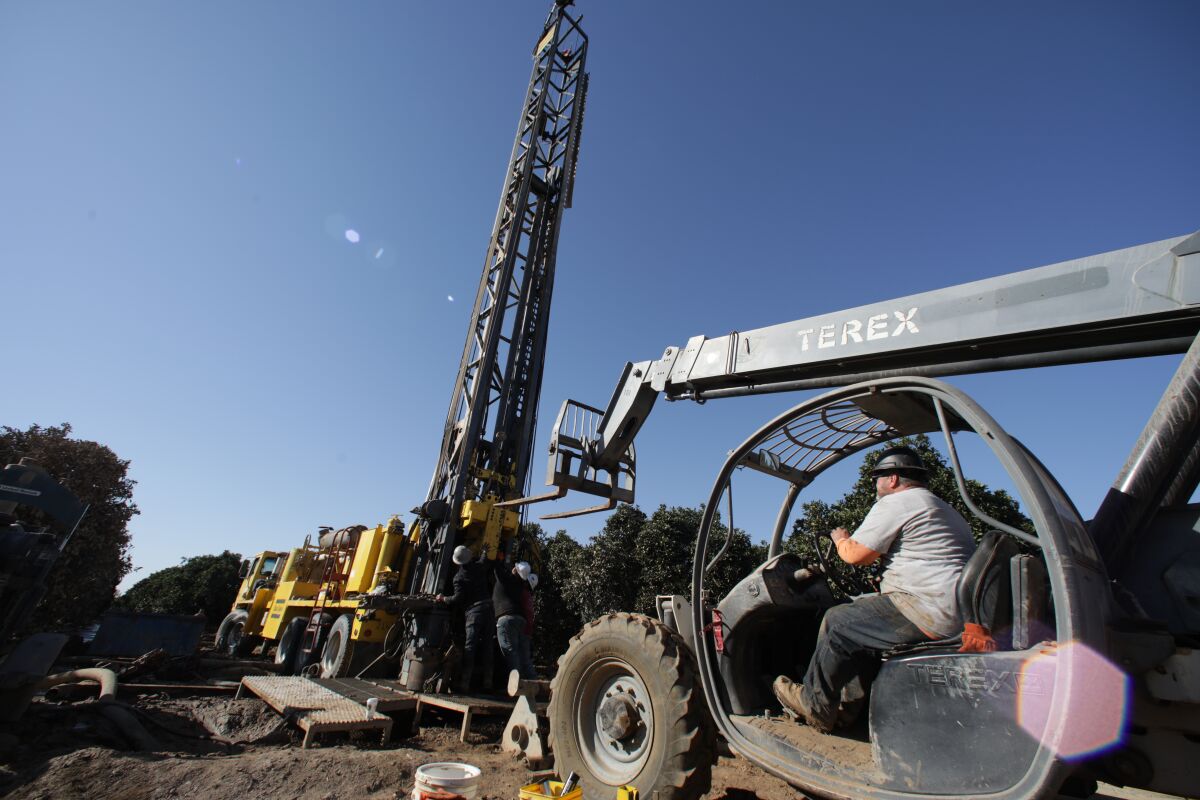 A worker uses construction equipment to drill a well