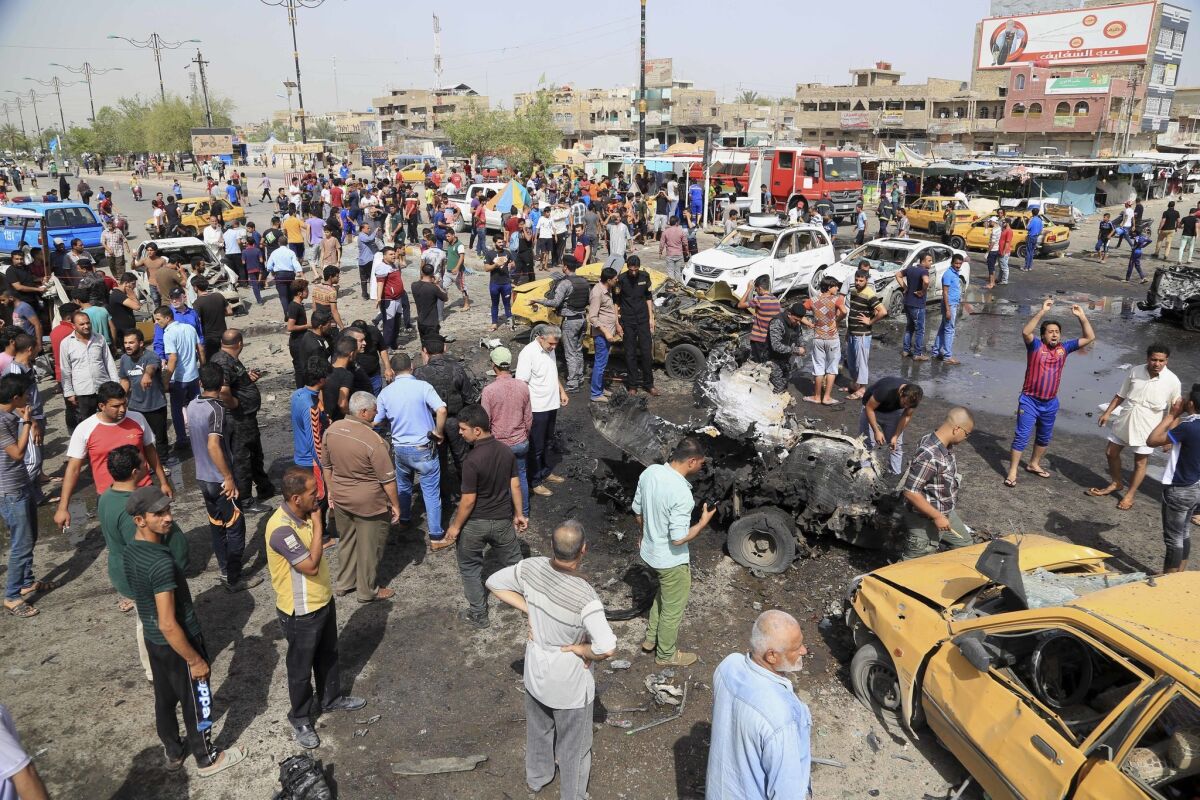 Security forces and citizens inspect the scene after a suicide car bombing hit a crowded outdoor market in Baghdad on May 17.