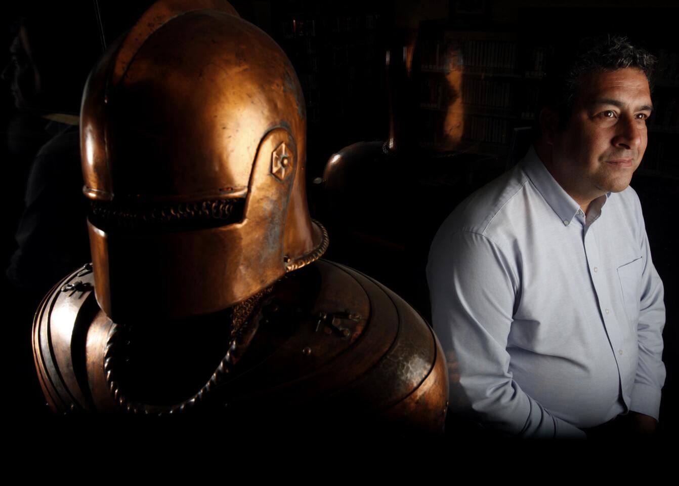 Daniel Hernandez, head of the Chicano Resource Center at the Anthony Quinn Library, stands next to a suit of armor given to him by actor John Barrymore.