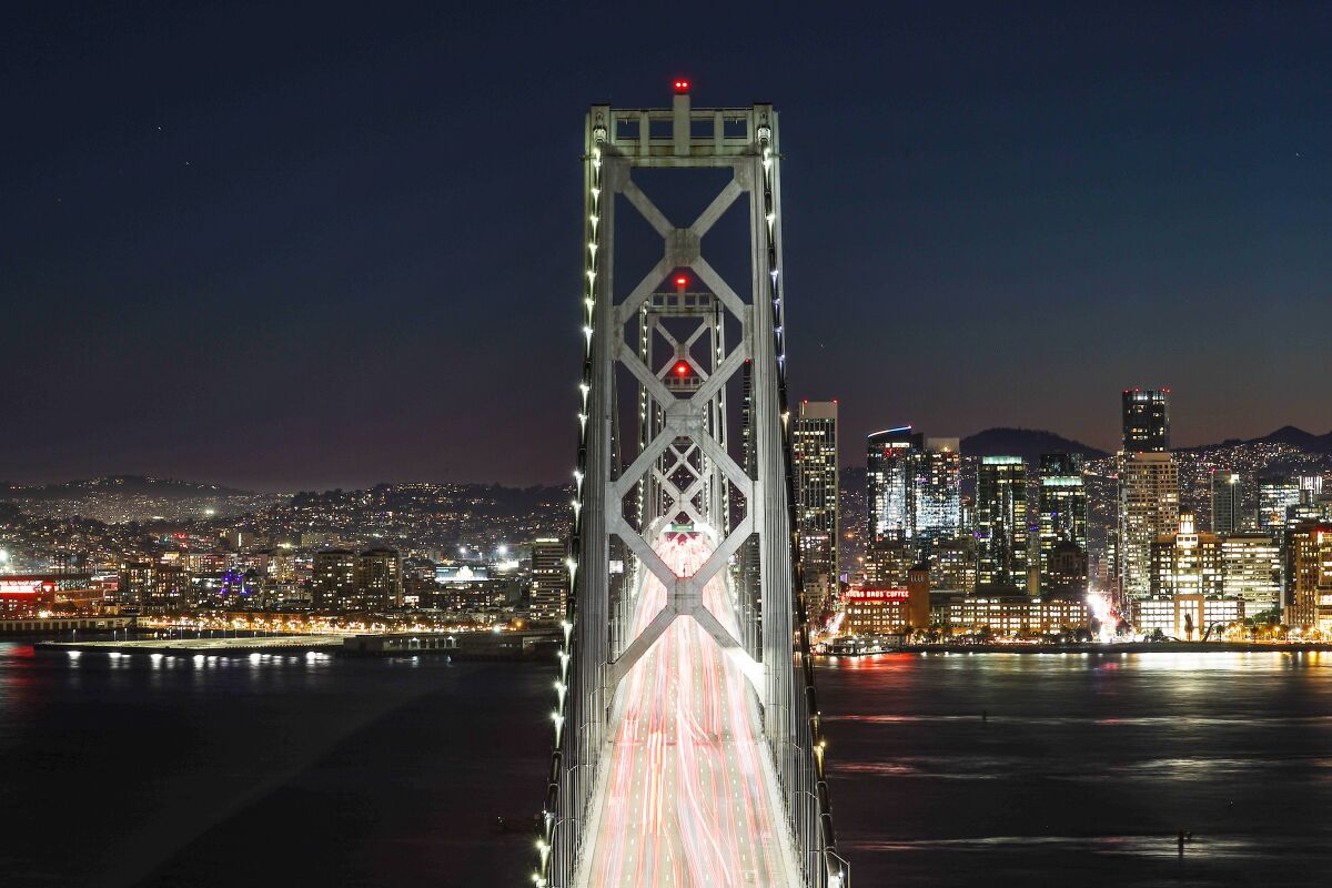 Vehicle headlights and taillights appear as long streaks on a bridge in a long exposure photo at night