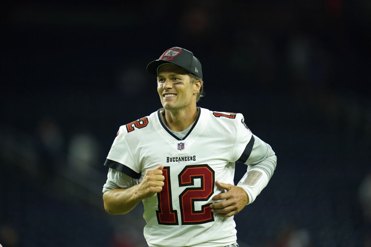 Tampa Bay Buccaneers quarterback Tom Brady smiles as he exits the field after a preseason game.