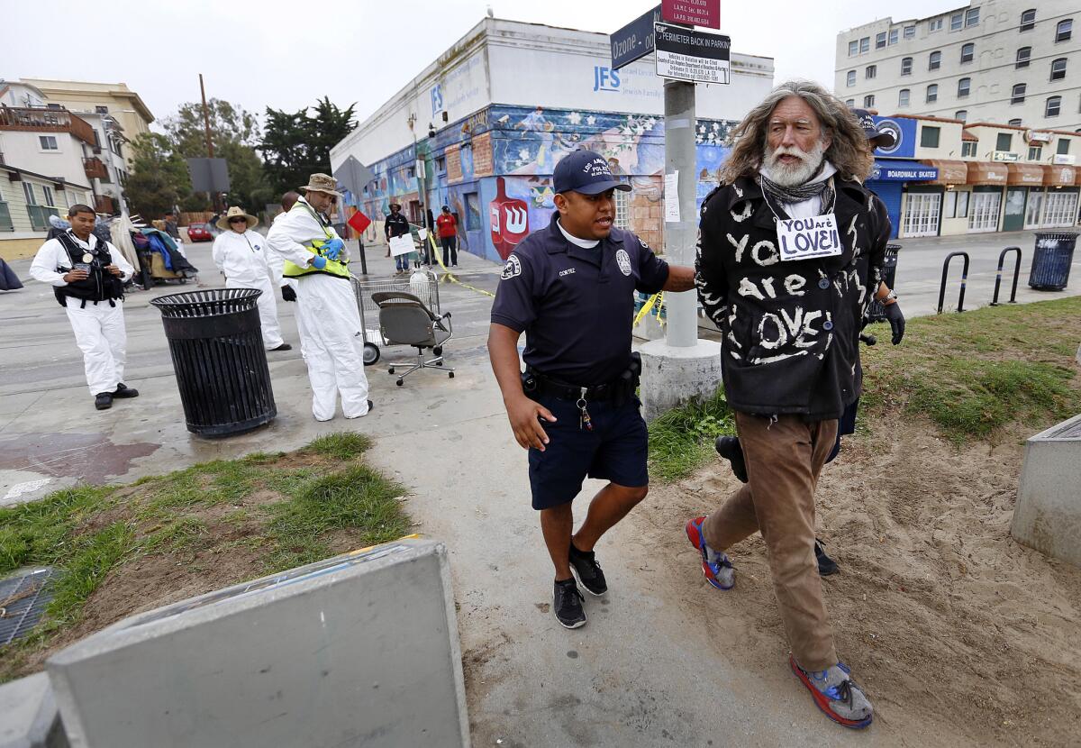 Homeless activist David Busch is led away by an LAPD officer during a 2015 sanitation sweep in Venice.