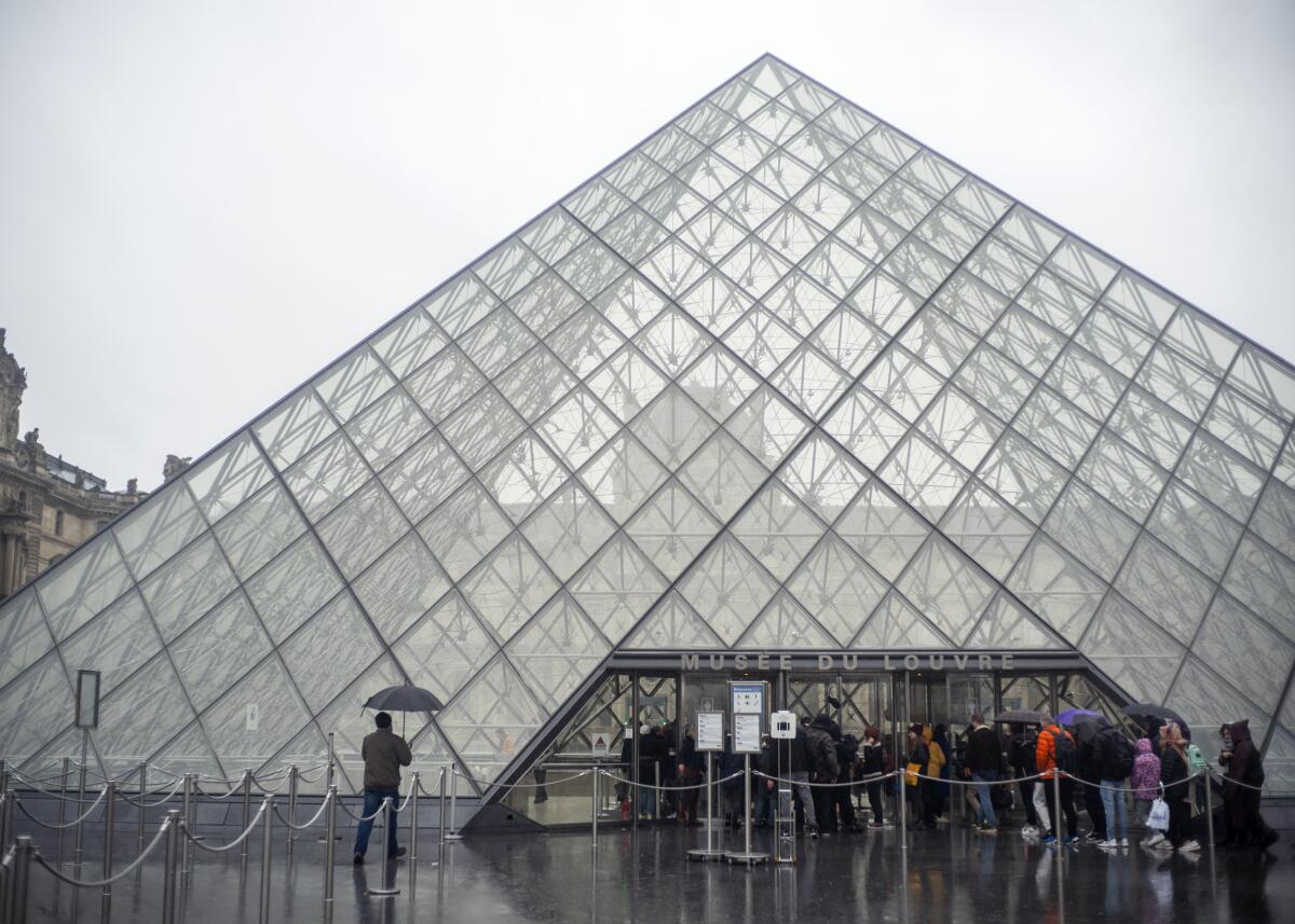 Tourists stand outside the Louvre Museum in Paris on Sunday. 