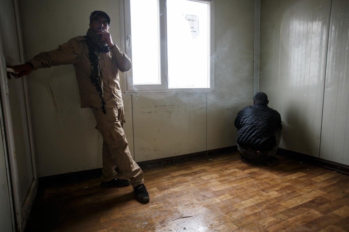 A man suspected of being an ISIS member, right, is put in a holding room before being sent to another facility for further questioning. (Marcus Yam / Los Angeles Times)