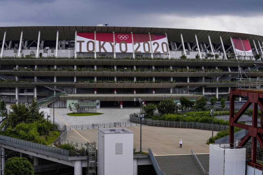 Un empleado camina frente al Estadio Nacional de Tokio, el miércoles 23 de junio de 2021, sede de las ceremonias de los Juegos Olímpicos de Tokio 2020. (AP Foto/Kiichiro Sato)