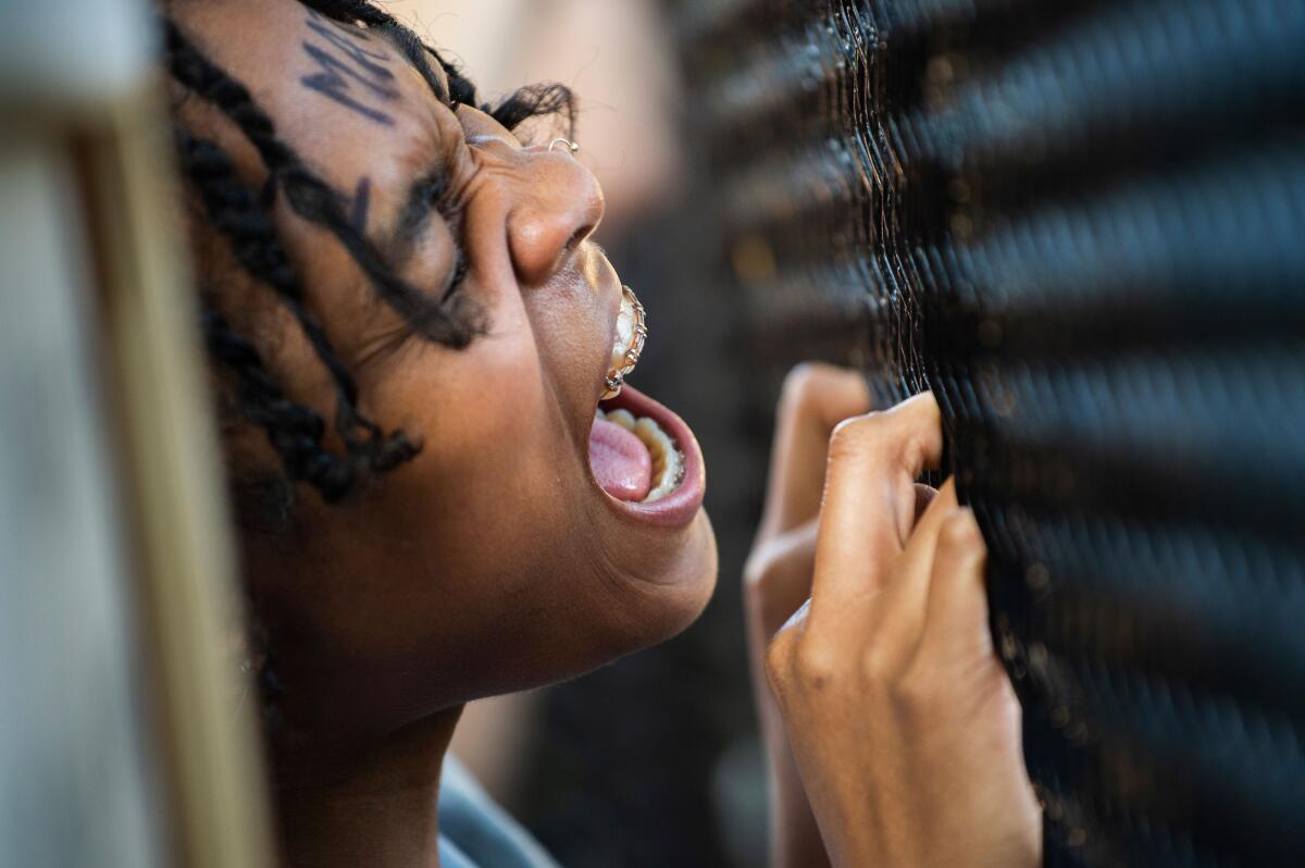 A woman shouts on June 2 at police officers from behind a metal fence near the White House.