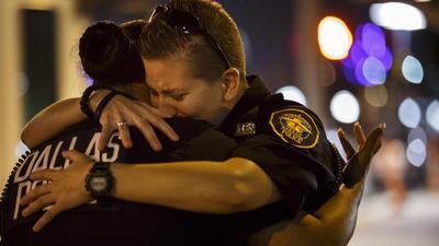 Police Officer Katherine Rhodes, right, embraces Officer Yuridia Morales at a memorial for the shooting victims.