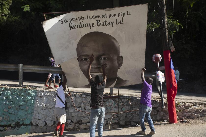 Supporters of slain Haitian President Jovenel Moise place a sign of him that reads "The purse of the people must remain with the people. Continue the fight," in the Petion-ville area of Port-au-Prince, Haiti, Thursday, July 7, 2022. A year has passed since Moise was assassinated at his private home. (AP Photo/Odelyn Joseph)