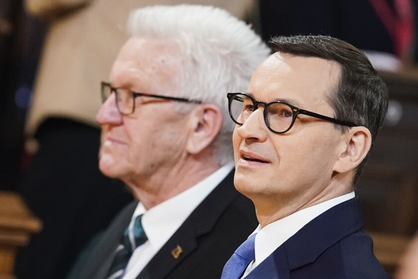 Poland's Prime Minister Mateusz Morawiecki, right, arrives with the Prime Minister of German federal state Baden Württemberg Winfried Kretschmann, left, at the Old Assembly Hall to deliver his speech about the 'Future Of Europe' at the University in Heidelberg, Germany, Monday, March 20, 2023. (Uwe Anspach/dpa via AP)