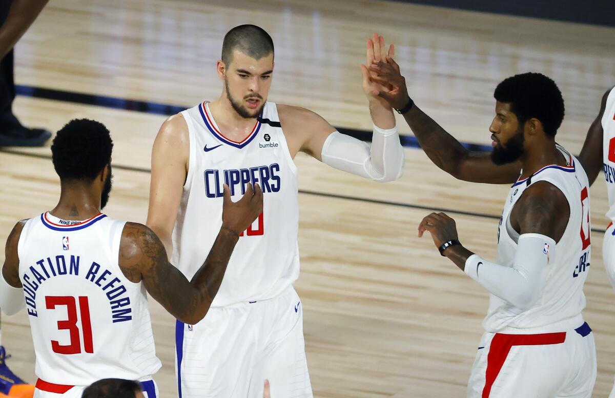 The Clippers' Paul George gives a high-five to Ivica Zubac, with Marcus Morris Sr., on Aug. 1, 2020.