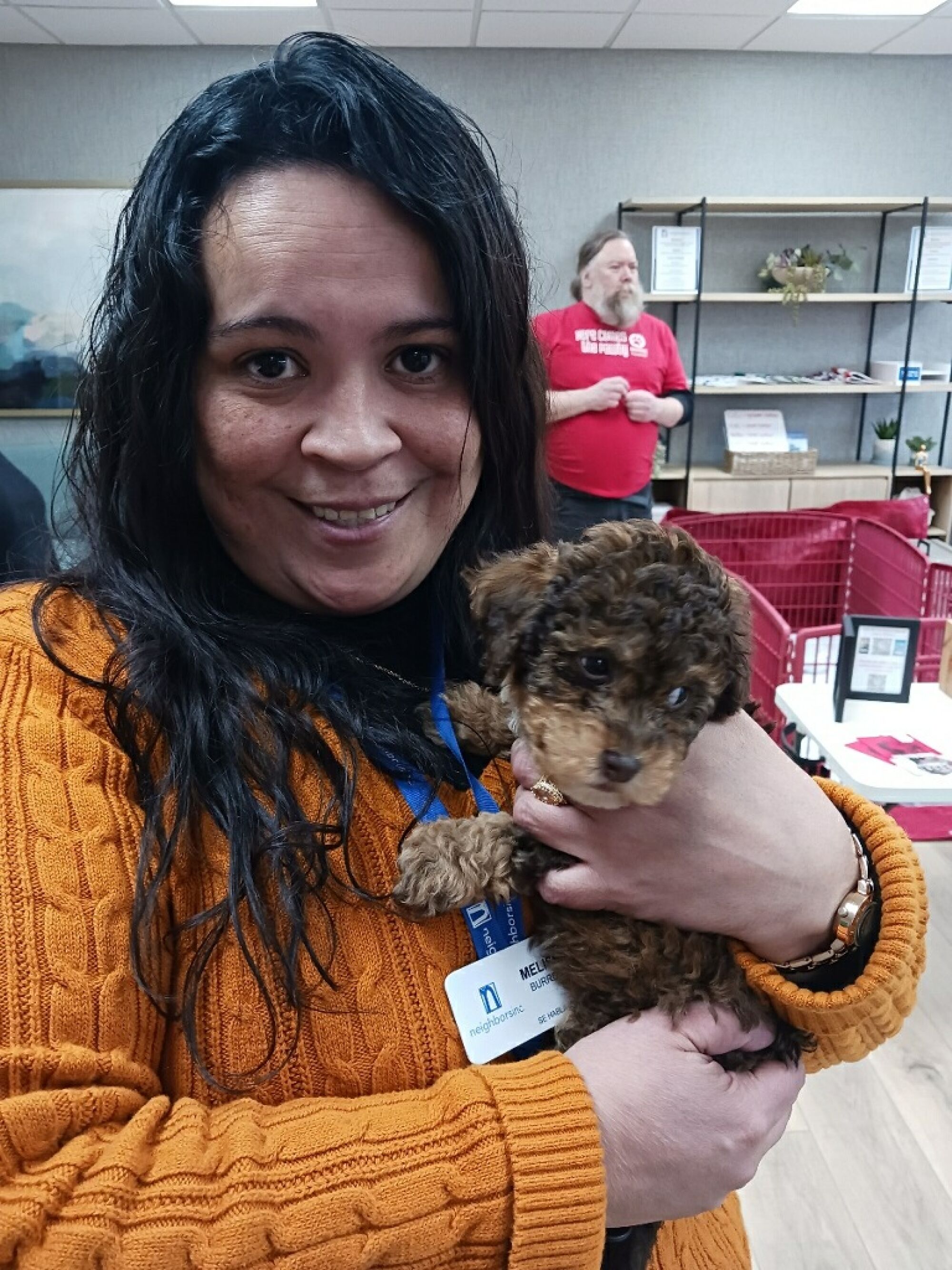 A woman holds a small brown puppy