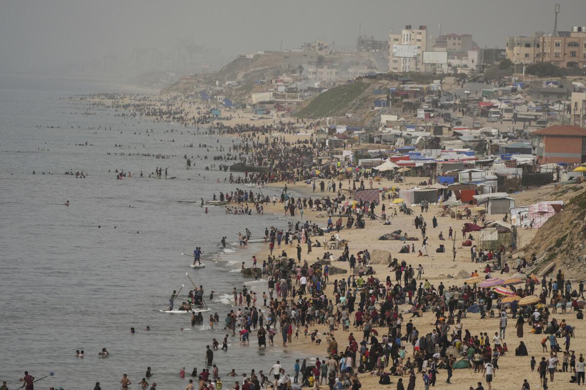 People crowd onto a beach along the Mediterranean Sea.