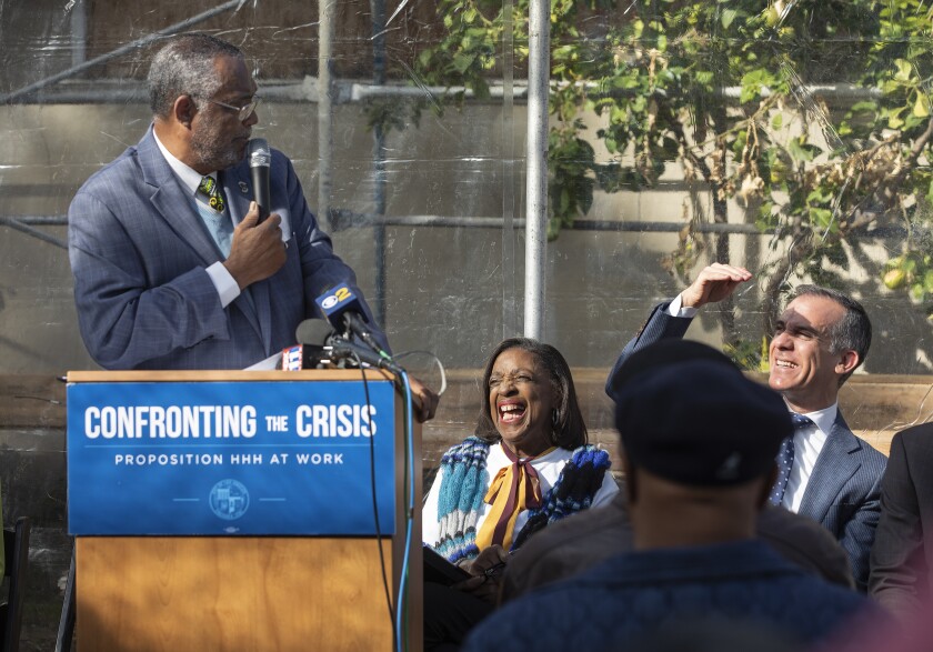 A man speaks at a podium with the banner "Confronting the crisis."