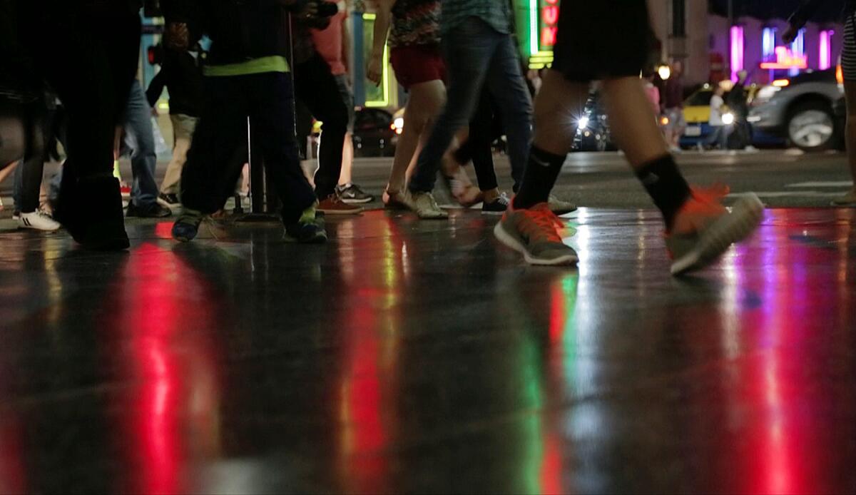 LOS ANGELES, CA - April 9, 2015: Pedestrians including many tourists walk through reflecting neon lights on the pavement after crossing the street at the intersection of Hollywood and Highland Boulevards on April 9, 2015 in Los Angeles, California. This intersection is one of the worst for pedestrian collisions.(Gina Ferazzi / Los Angeles Times)