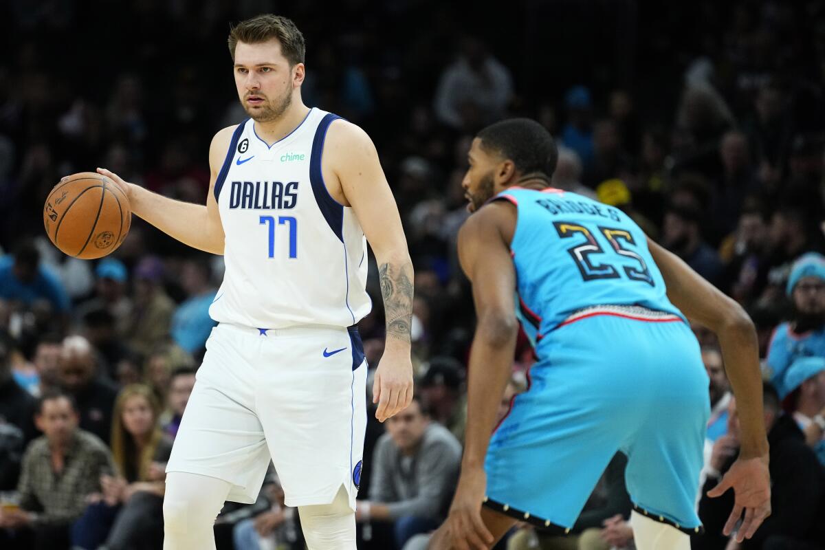 Dallas Mavericks guard Luka Doncic (77) moves the ball up court as Phoenix Suns forward Mikal Bridges (25) defends during the first half of an NBA basketball game, Thursday, Jan. 26, 2023, in Phoenix. (AP Photo/Matt York)