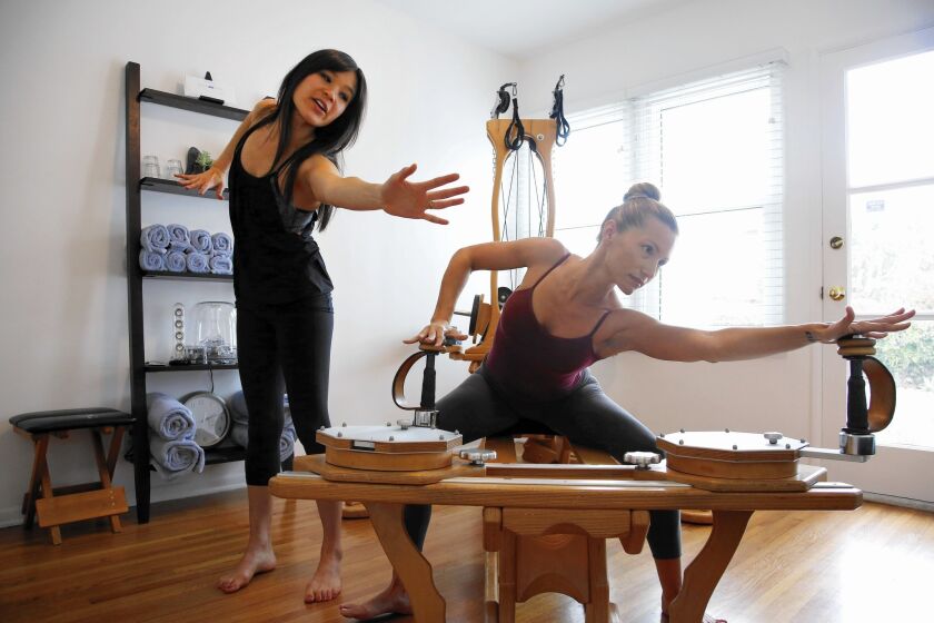 Deandra Lee, left, demonstrates the movement client Danielle Thulin should be doing on the Gyrotonic pulley tower.