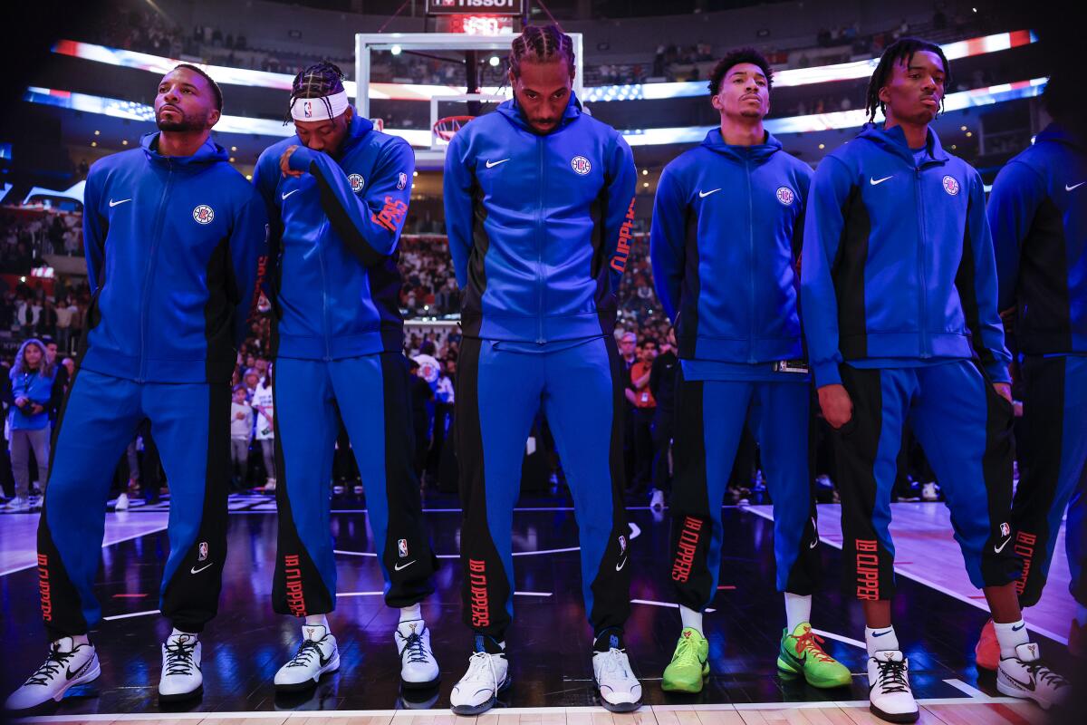 Clippers forward Kawhi Leonard, center, joins teammates standing on the court for the national anthem