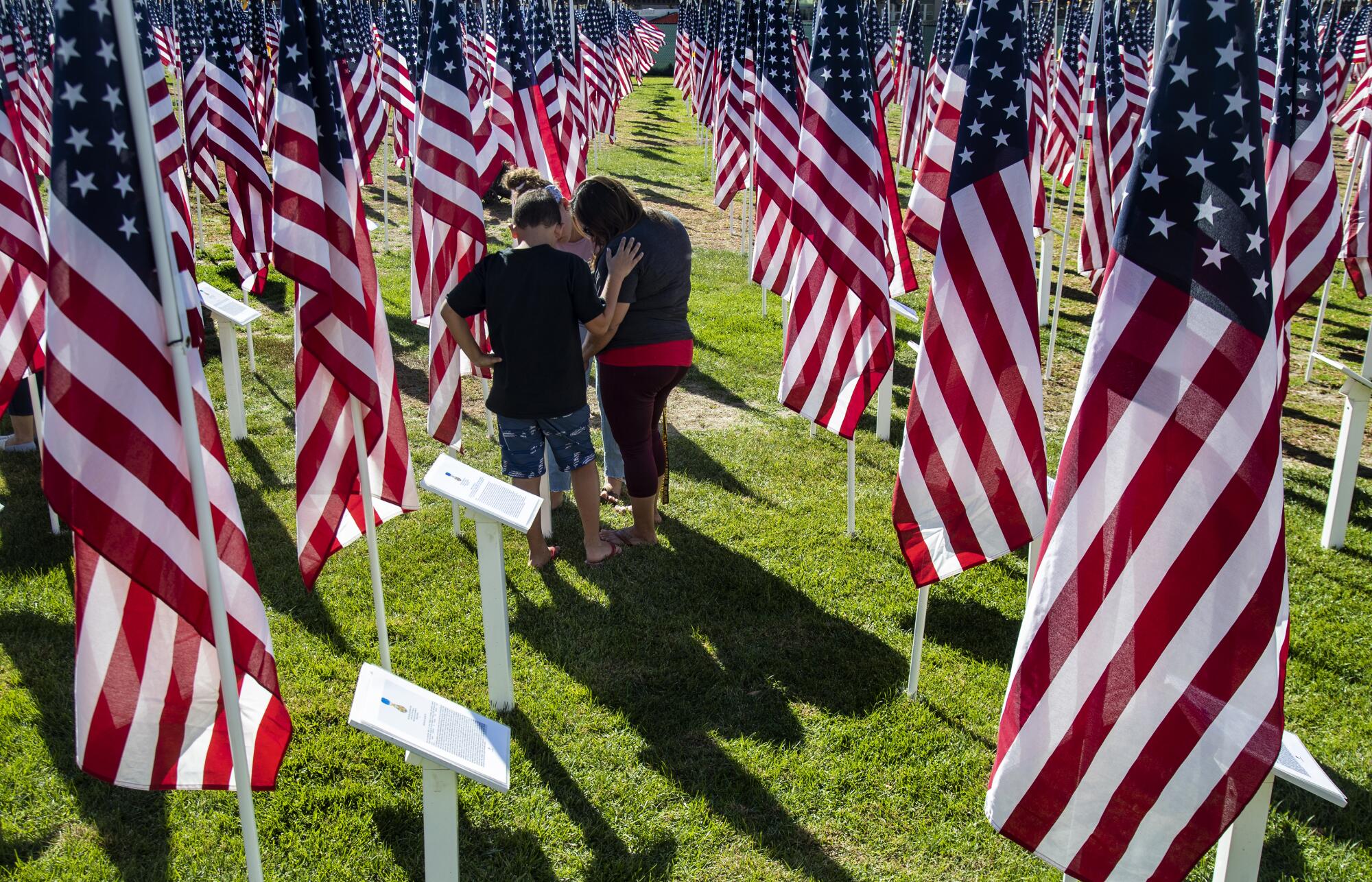 A family reads a soldier's placard at the Field of Honor on Veterans Day in Murrieta.