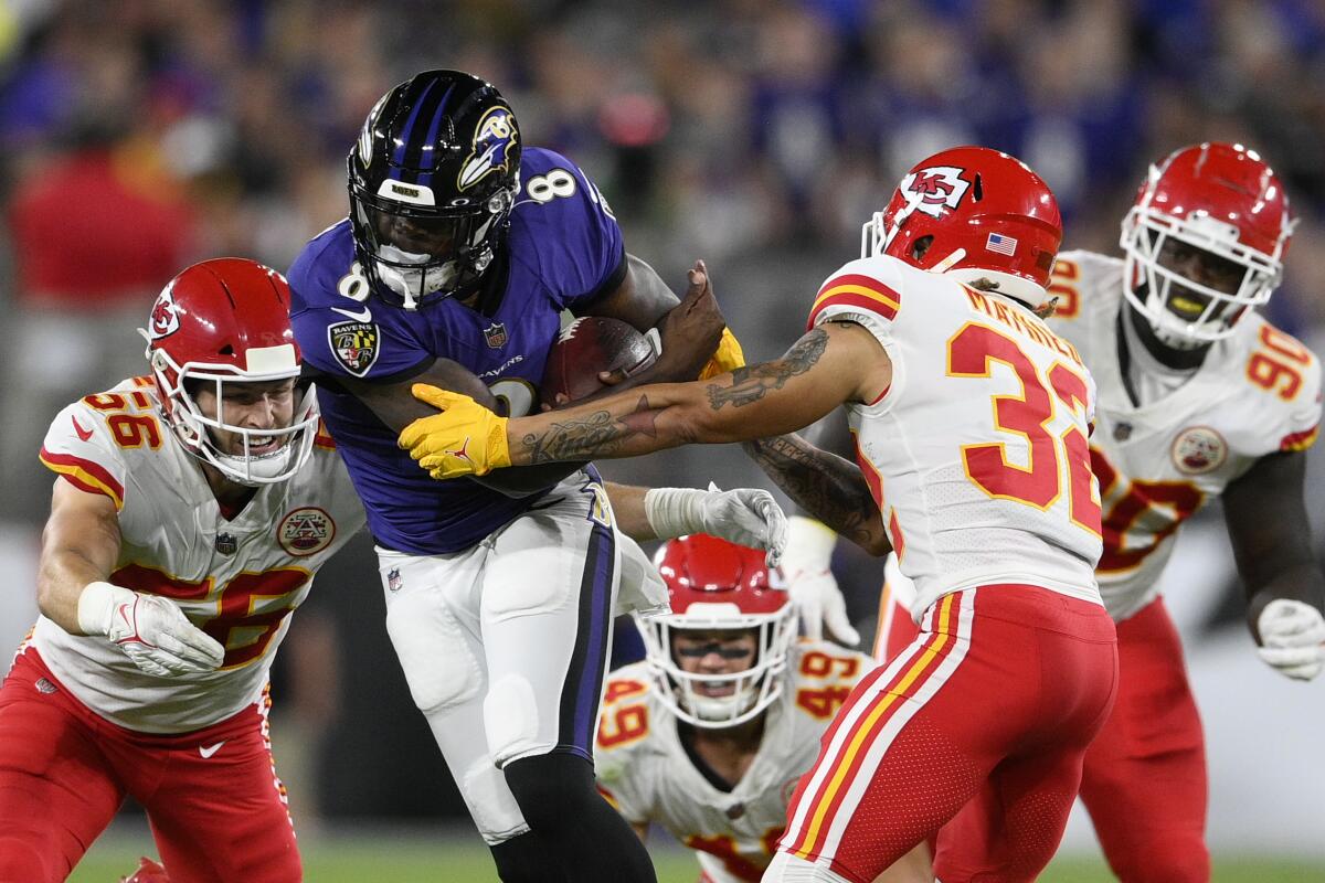 El quarterback de los Ravens Lamar Jackson (8) corre entre cuatro defensores de los Chiefs 