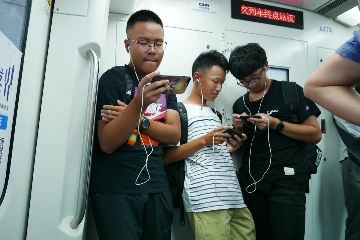 Young people read on their smartphones while riding a train in Wuhan, China, in 2018. 